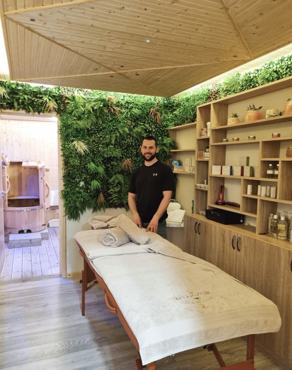 The massage therapist at Pressure London Massage in the treatment room, beside the green living wall